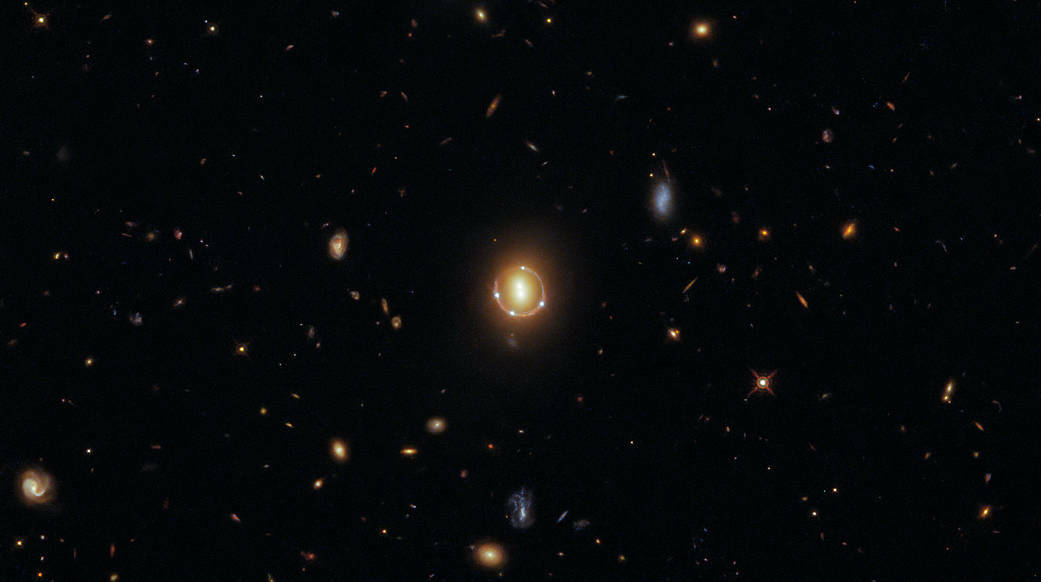 Look at the center of this image and you'll see two bright spots: a pair of galaxies. Surrounding those two spots are four points of light. There's also a faint fifth point in the center as seen by Hubble. All five points are actually the same quasar, a celestial object that emits a lot of energy. The quasar is further away from Earth than the enormous galaxies, which are causing light from the quasar to bend in such a way that it appears to multiply.