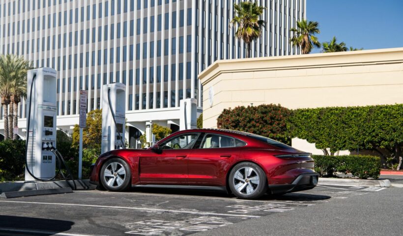 A red car in a parking lot plugged into a charger.