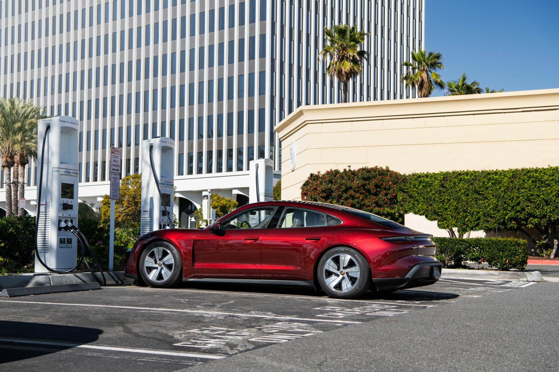 A red car in a parking lot plugged into a charger.