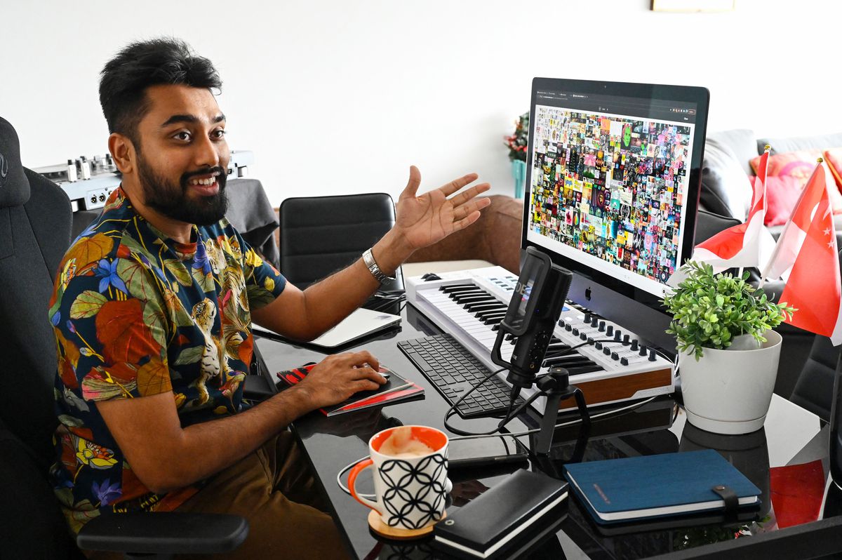 A man gestures at artwork on his computer screen.