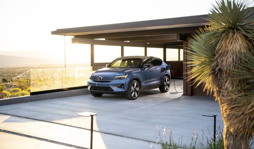 A car facing forward while in an open glass garage with a yucca plant on the right side.