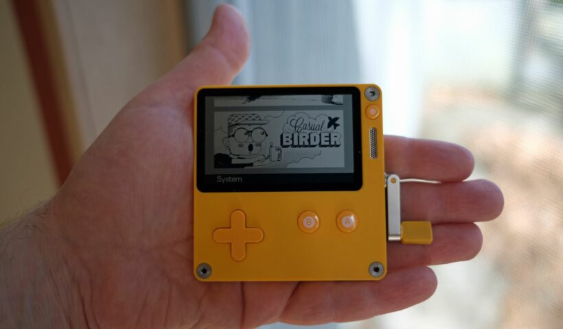 A Playdate gaming device clutched in someone's palm.