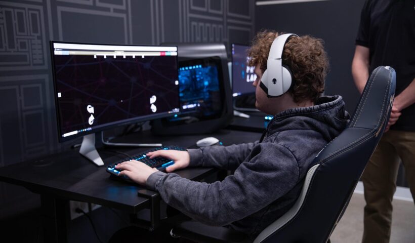 Esports pro Bradley Bennyworth sits at a desktop computer, wearing headphones, as he takes the NeurOlympics test.
